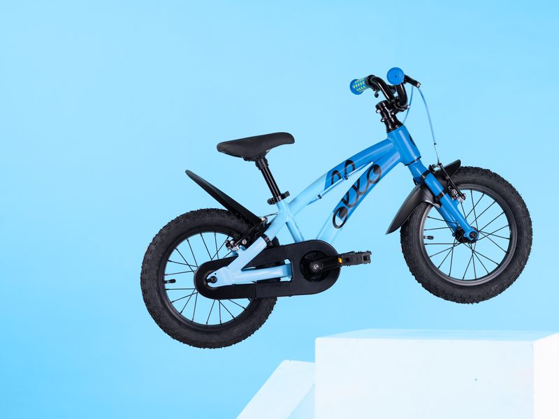 Blaues Ollo-Kinderfahrrad vor hellblauem Hintergrund